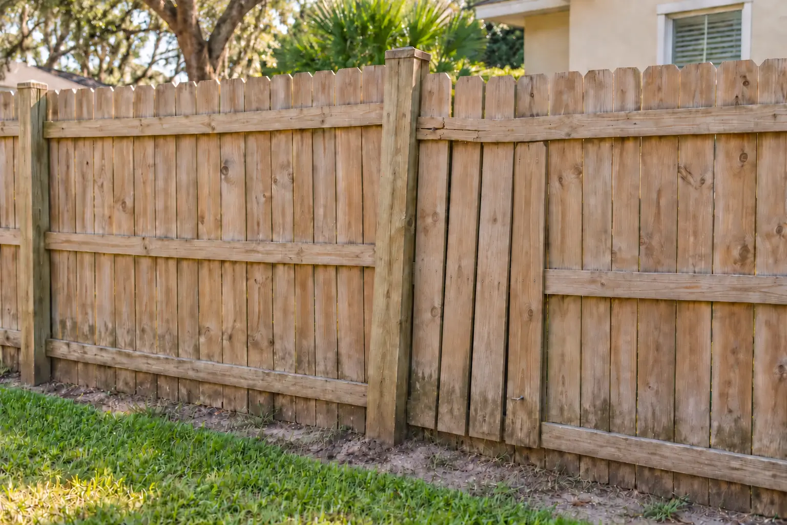 Leaning wood fence section with a damaged rail and loose boards